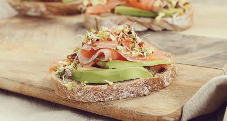 Broodje Gerookte Zalm met Avocado en Dille op een houten bord